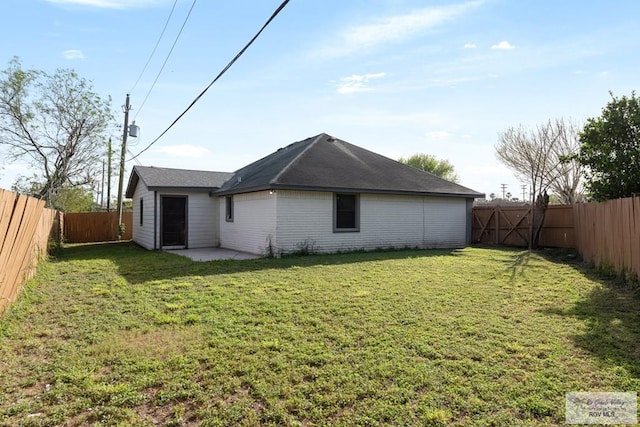 rear view of property featuring a patio, a lawn, and a fenced backyard