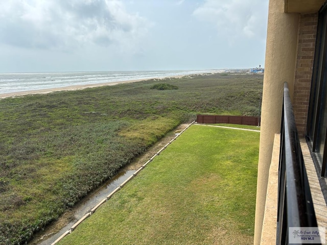 view of yard with a beach view, fence, and a water view