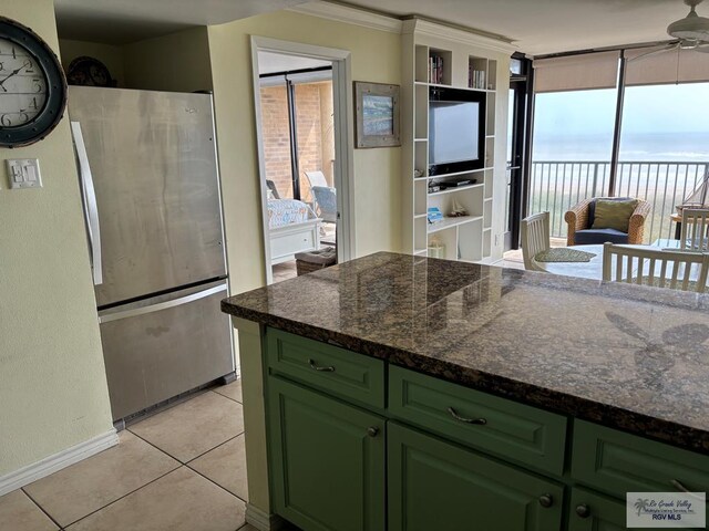 110 Padre Blvd Unit 407, South Padre Island, TX 78597 - kitchen featuring dark stone countertops, a ceiling fan, light tile patterned floors, freestanding refrigerator, and green cabinets