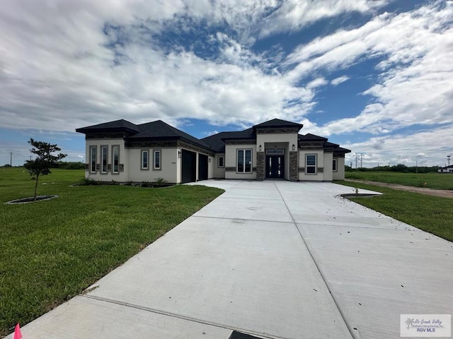 prairie-style home with a garage, concrete driveway, and a front yard