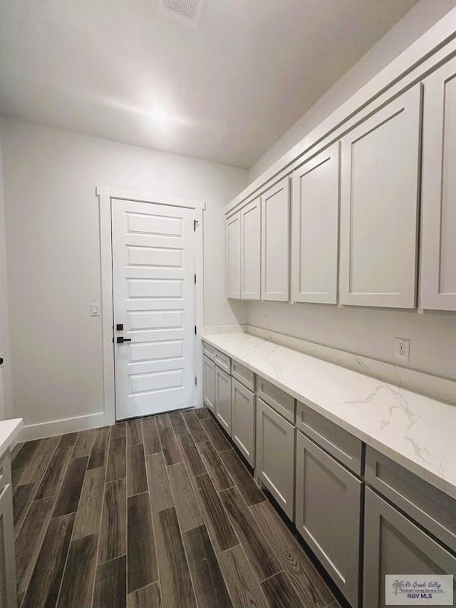 laundry area with wood finish floors, visible vents, and baseboards