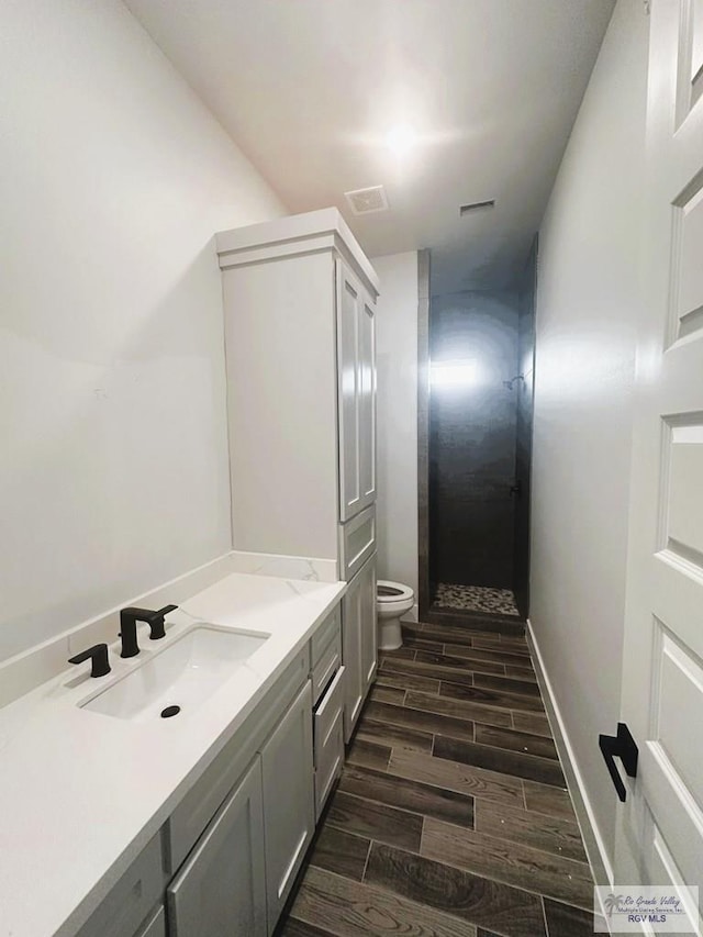 bathroom with walk in shower, vanity, wood-type flooring, and toilet