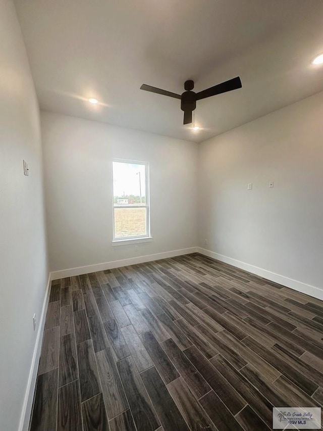 spare room with dark wood-style floors, a ceiling fan, and baseboards