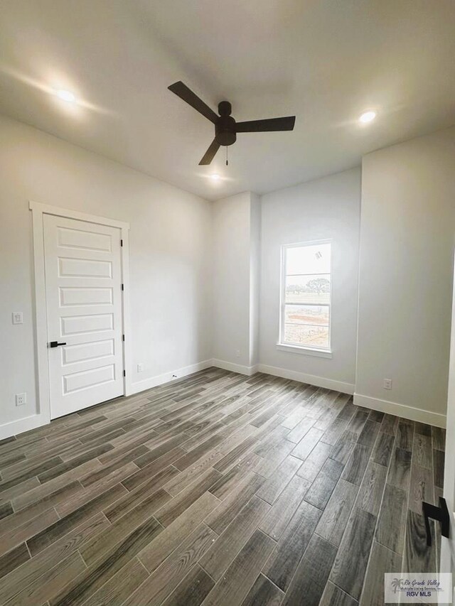 empty room with dark hardwood / wood-style flooring and ceiling fan