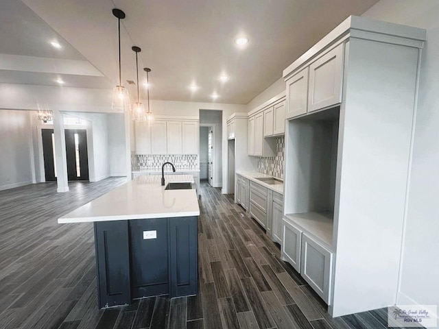 kitchen featuring wood finish floors, a center island with sink, tasteful backsplash, recessed lighting, and a sink