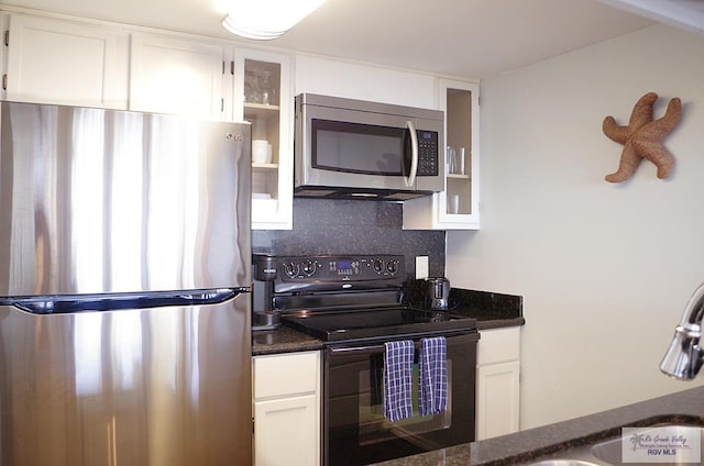 kitchen featuring tasteful backsplash, stainless steel appliances, sink, dark stone countertops, and white cabinets