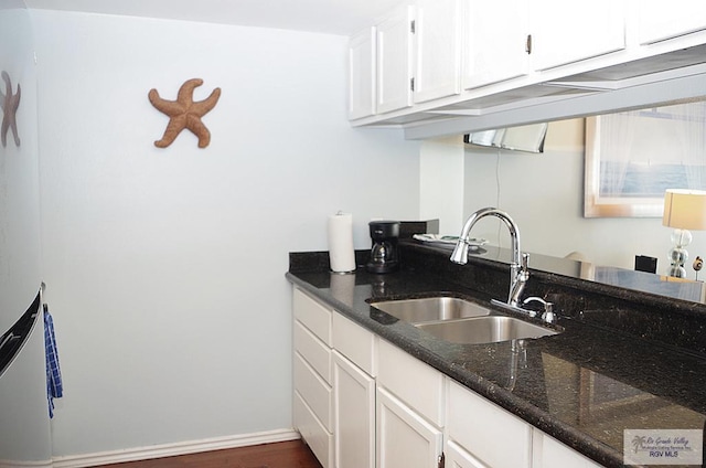 kitchen featuring white cabinets, dark wood-type flooring, dark stone counters, and sink