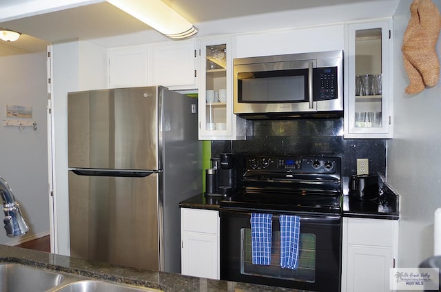 kitchen with tasteful backsplash, dark stone counters, white cabinets, and stainless steel appliances