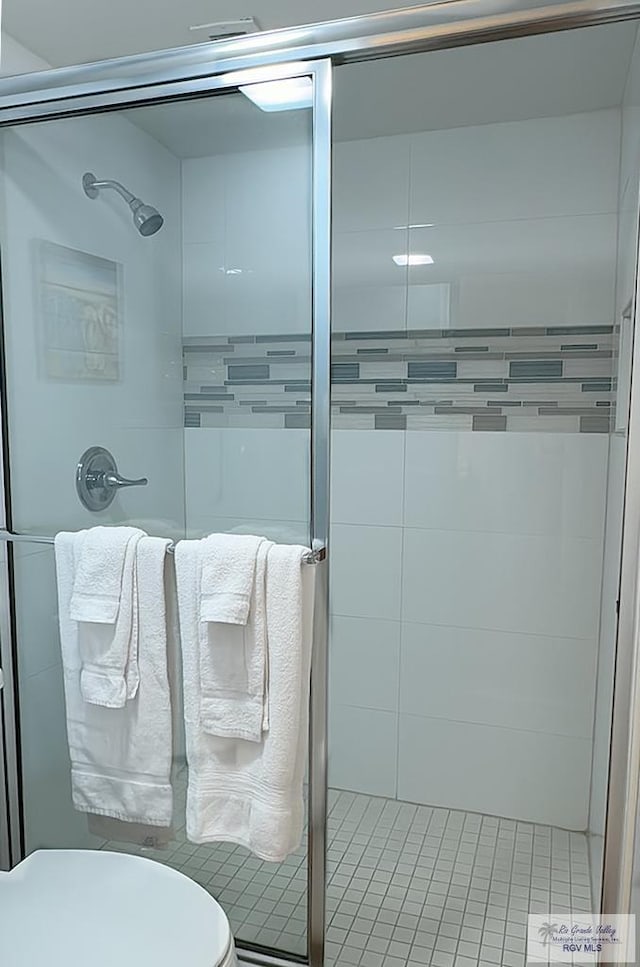 bathroom featuring tile patterned flooring, toilet, and an enclosed shower