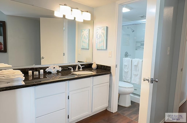 bathroom with vanity, hardwood / wood-style flooring, toilet, and a shower with door