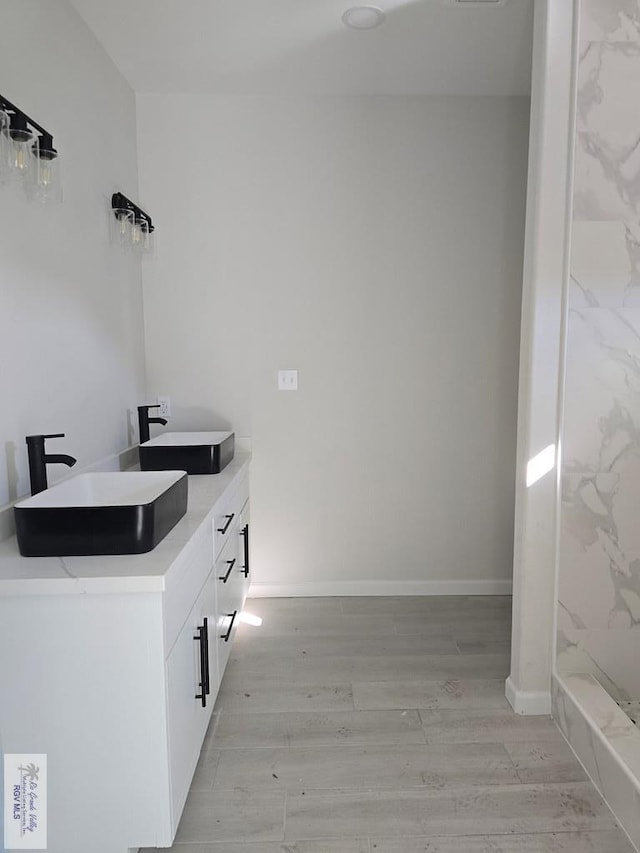 bathroom featuring hardwood / wood-style flooring, vanity, and a shower