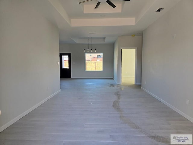 empty room featuring light hardwood / wood-style floors, a raised ceiling, and ceiling fan