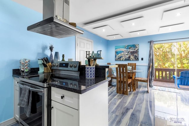 kitchen with dark stone countertops, wood finished floors, island range hood, stainless steel range with electric cooktop, and white cabinets