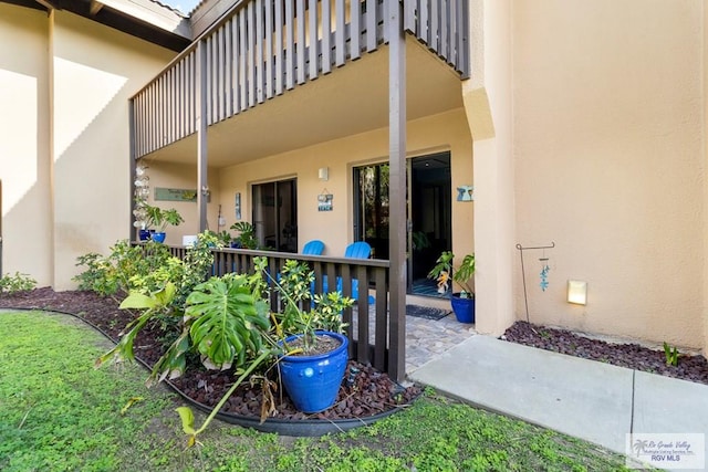 entrance to property with stucco siding and a balcony
