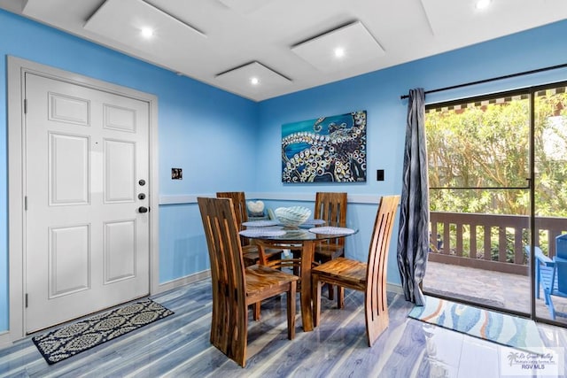 dining space with recessed lighting, a wainscoted wall, and wood finished floors