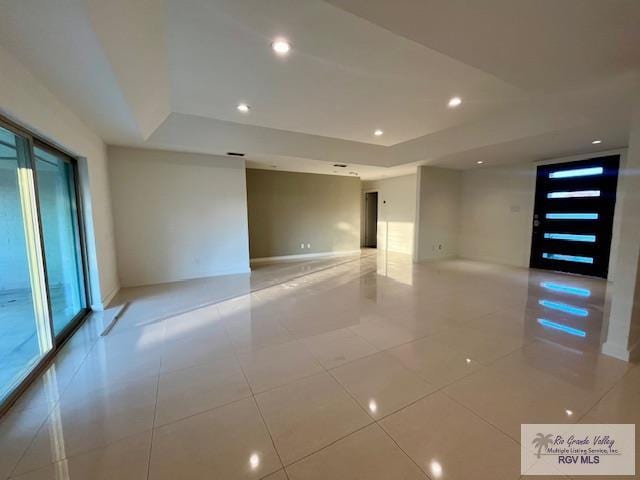 spare room with a raised ceiling and light tile patterned flooring