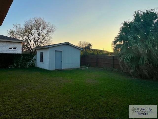 yard at dusk featuring a storage shed