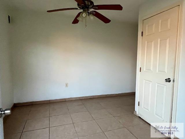 tiled spare room with ceiling fan