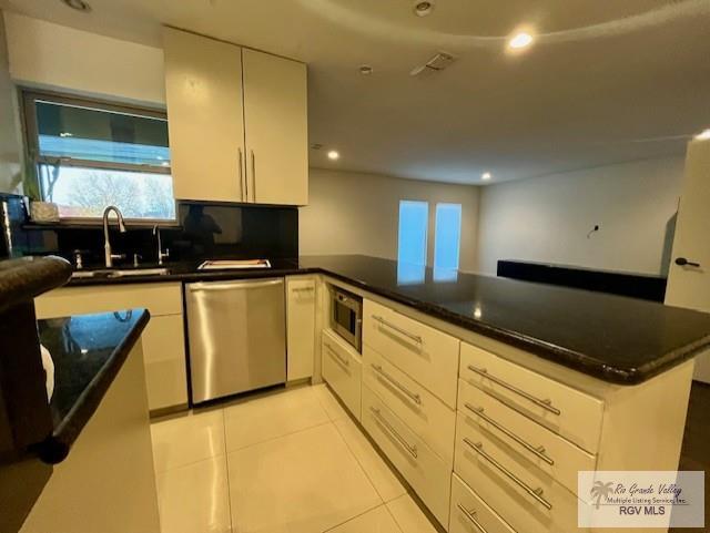 kitchen with sink, stainless steel appliances, tasteful backsplash, light tile patterned flooring, and kitchen peninsula