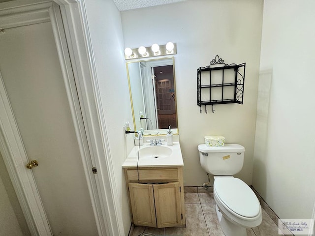 bathroom with toilet, vanity, and tile patterned floors