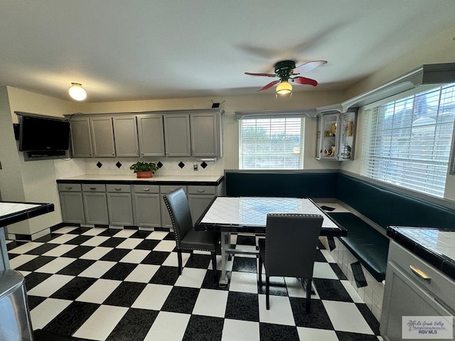 kitchen with gray cabinetry, tile counters, ceiling fan, and tasteful backsplash