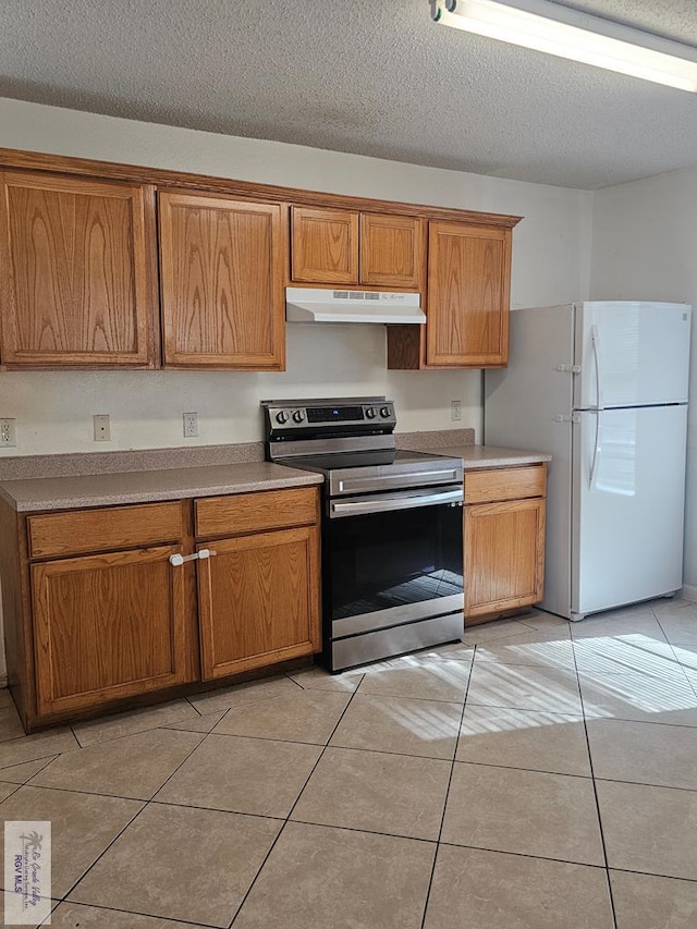 1149 Champlain Dr, Brownsville, TX 78526 - kitchen featuring white fridge, light tile patterned flooring, a textured ceiling, and stainless steel stove