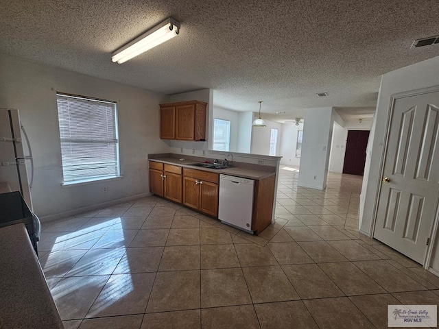 1149 Champlain Dr, Brownsville, TX 78526 - kitchen featuring white appliances, sink, light tile patterned floors, decorative light fixtures, and kitchen peninsula