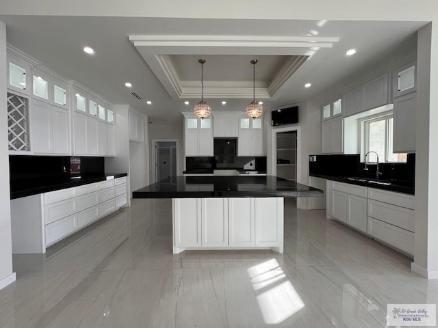 kitchen featuring dark countertops, white cabinetry, a raised ceiling, and decorative backsplash