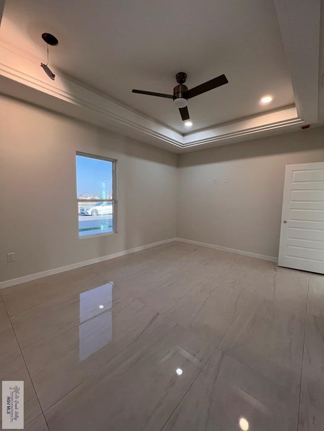 spare room featuring recessed lighting, a raised ceiling, a ceiling fan, and baseboards