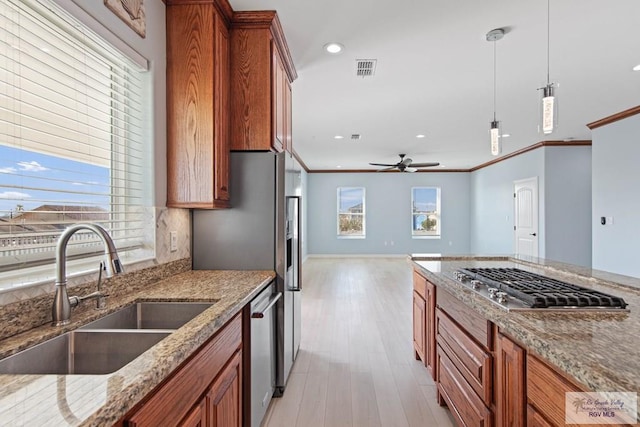 1013 Tarpon Ave, Port Isabel, TX 78578 - kitchen featuring a sink, brown cabinetry, appliances with stainless steel finishes, light wood finished floors, and decorative light fixtures