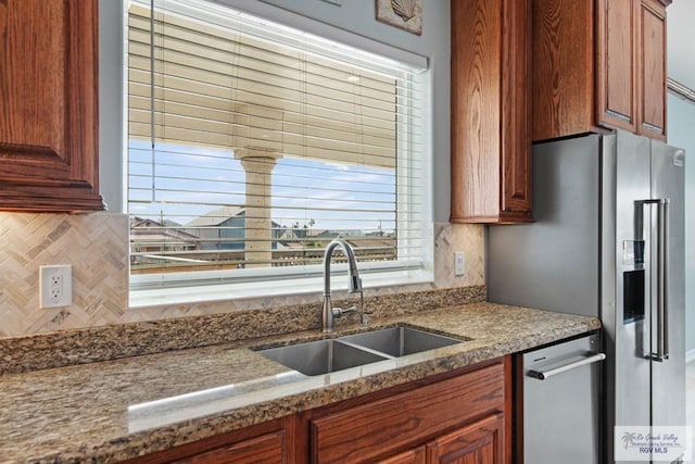 1013 Tarpon Ave, Port Isabel, TX 78578 - kitchen featuring a sink, decorative backsplash, appliances with stainless steel finishes, brown cabinetry, and light stone counters