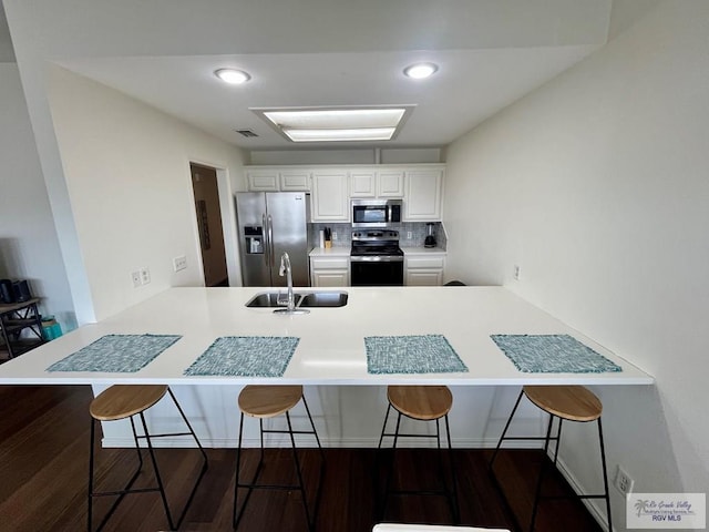 77 Santa Isabel Blvd Unit K 6, Laguna Vista, TX 78578 - kitchen featuring appliances with stainless steel finishes, a peninsula, a breakfast bar, white cabinetry, and dark wood-style flooring