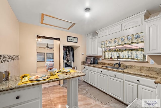 kitchen with light stone counters, sink, and white cabinets