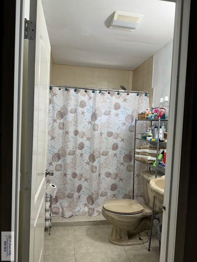 bathroom with a shower with shower curtain, tile patterned floors, and toilet