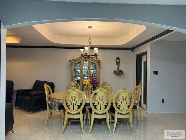 tiled dining area featuring a raised ceiling and a chandelier