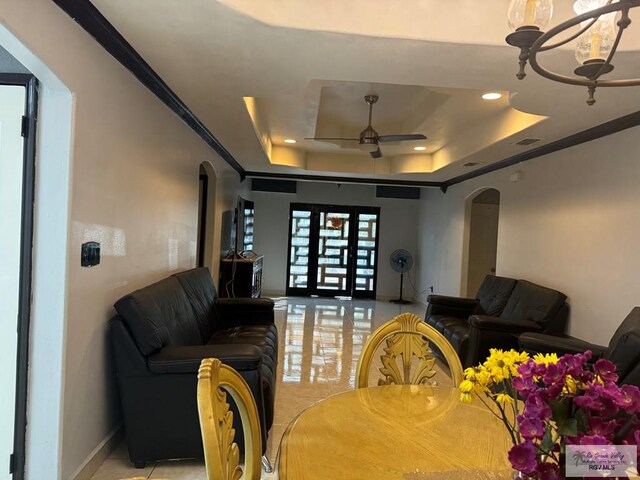 interior space with a tray ceiling, ceiling fan with notable chandelier, and ornamental molding