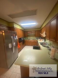 kitchen with kitchen peninsula, stainless steel fridge, and ventilation hood