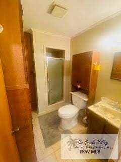 bathroom with a shower, tile patterned flooring, ornamental molding, and toilet