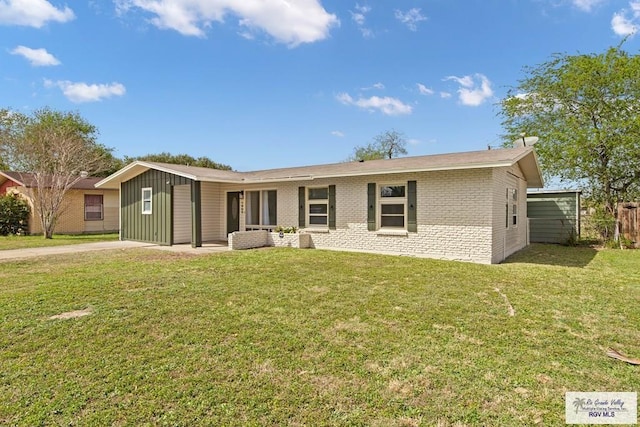 1909 E Madison Ave, Harlingen, TX 78550 - view of front facade featuring brick siding, a front lawn, board and batten siding, and driveway