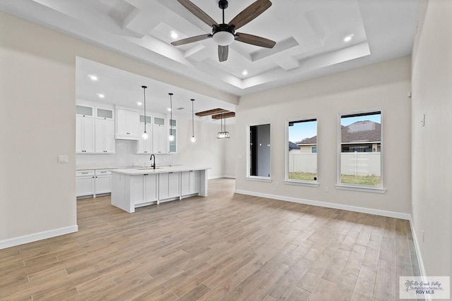 unfurnished living room featuring ceiling fan, sink, and coffered ceiling