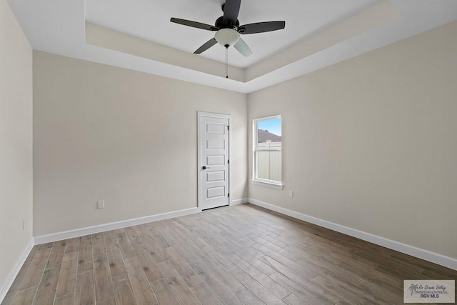 spare room featuring a tray ceiling, ceiling fan, and light hardwood / wood-style flooring