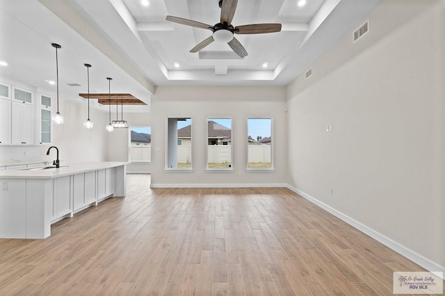 unfurnished living room with ceiling fan, sink, and light hardwood / wood-style floors