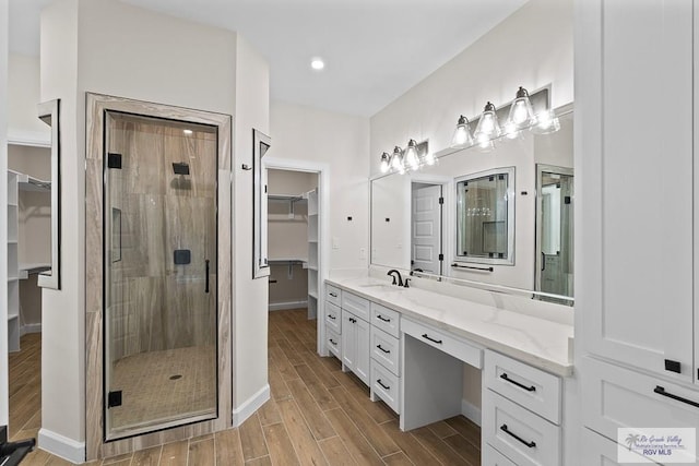 bathroom featuring a shower with door and vanity