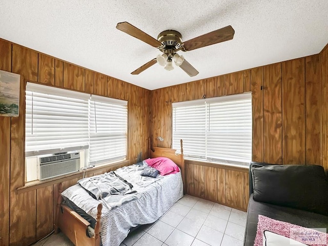 420 4th St, Elsa, TX 78543 - bedroom featuring wooden walls, cooling unit, a textured ceiling, light tile patterned flooring, and ceiling fan