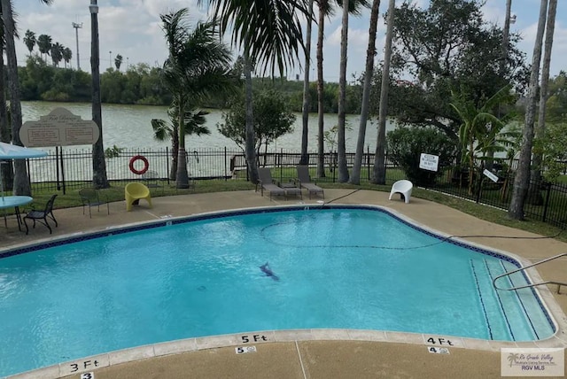 view of swimming pool with a patio area and a water view