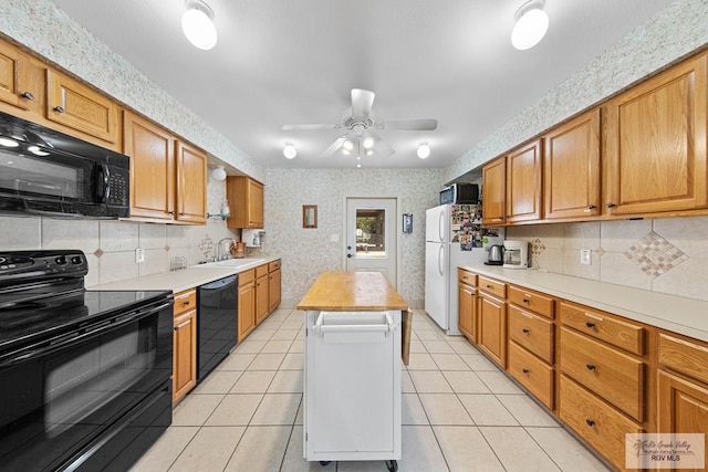 kitchen with butcher block counters, sink, light tile patterned flooring, and black appliances