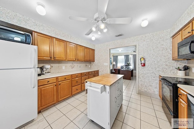 kitchen featuring ceiling fan, black appliances, light tile patterned floors, butcher block countertops, and a kitchen island