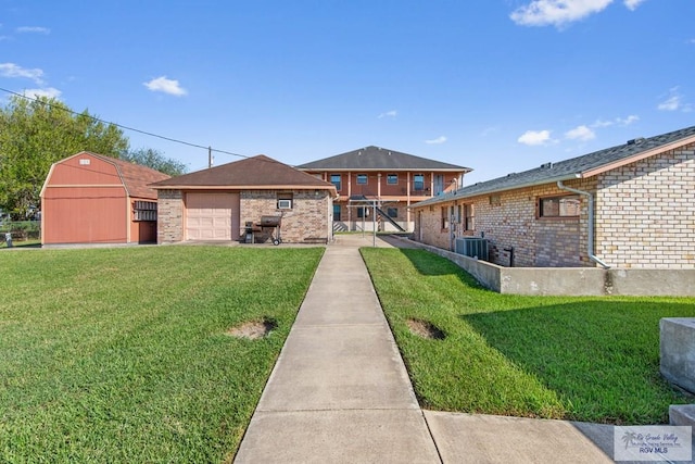 view of front of home featuring a front yard, a garage, cooling unit, and an outdoor structure