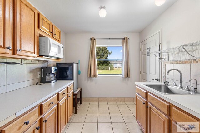 kitchen featuring decorative backsplash, light tile patterned floors, and sink