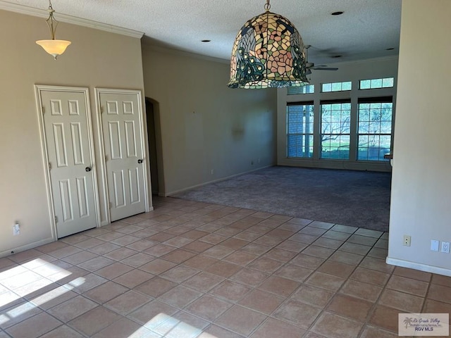 empty room with a textured ceiling, arched walkways, crown molding, light tile patterned floors, and light colored carpet